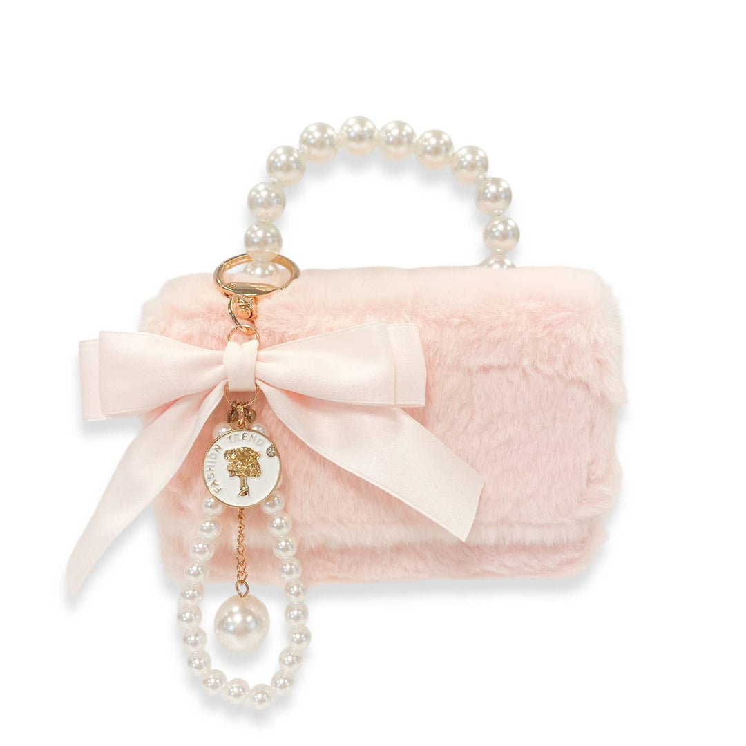 Pink fluffy handbag with pearl handle and decorative bow on a white background