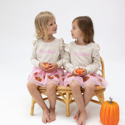 2 little girls modeling the Autumn outfit: Thankful top with pumpkin tutu skirt. 