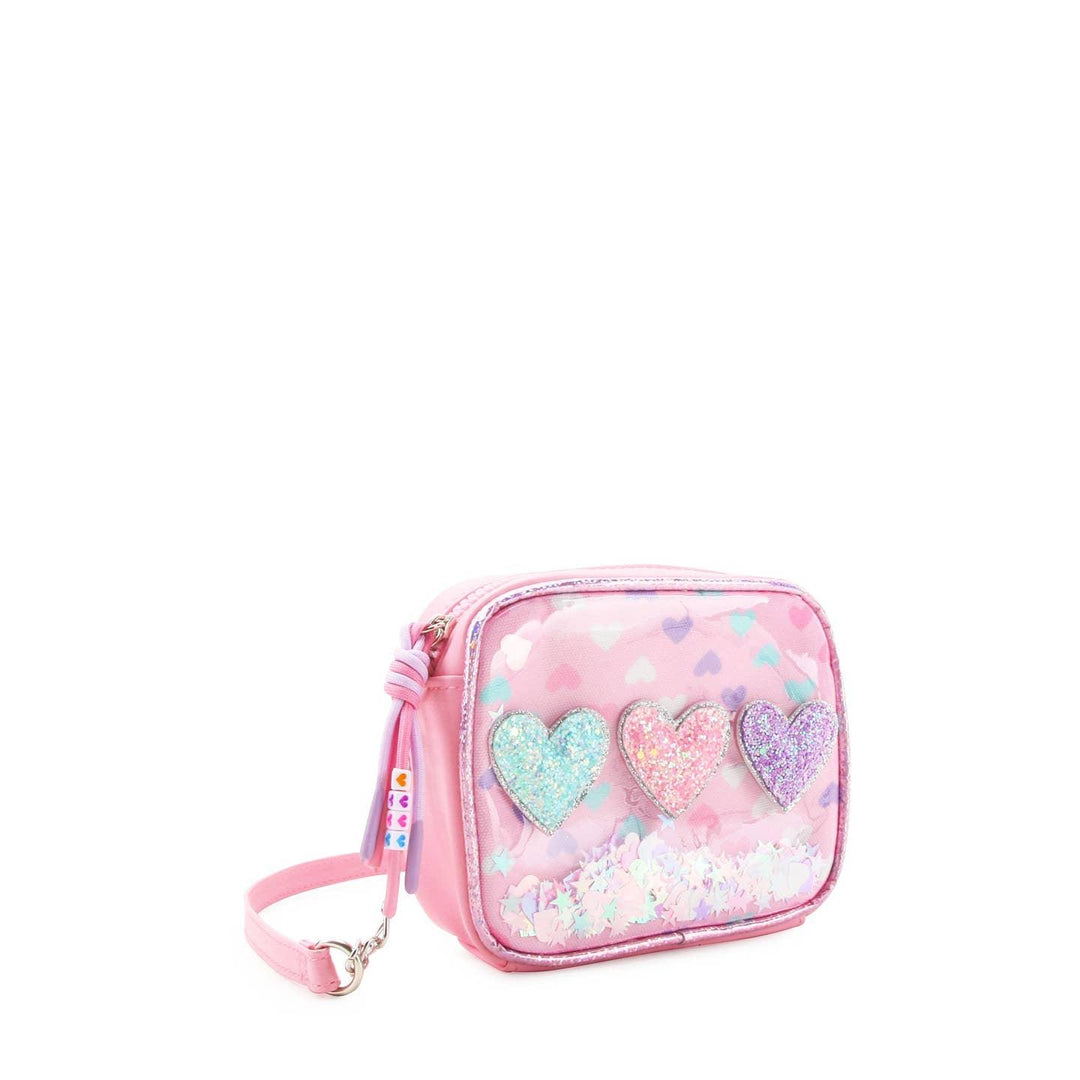 pink corssbody bag with 3 glitter heart appliques across the center of the front of the bag. confetti on the inside of the bag