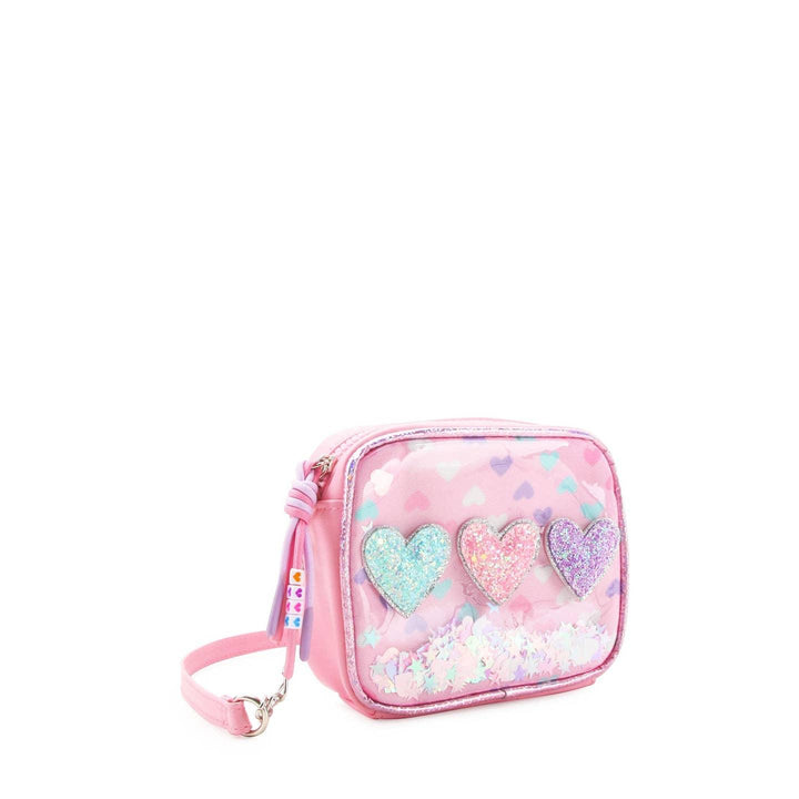 pink corssbody bag with 3 glitter heart appliques across the center of the front of the bag. confetti on the inside of the bag