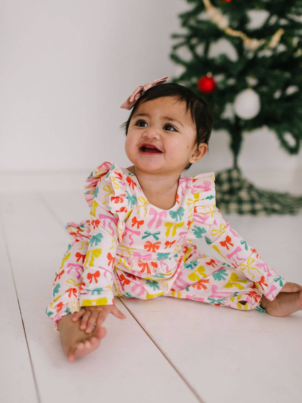 Child wearing a colorful outfit with a Christmas tree in the background