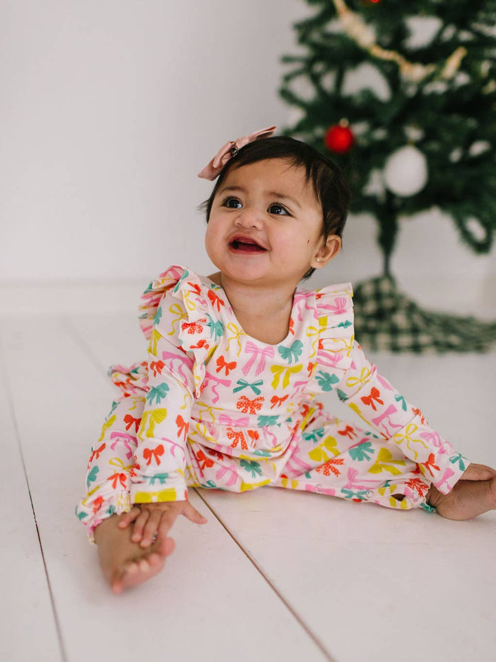 Child wearing a colorful outfit with a Christmas tree in the background