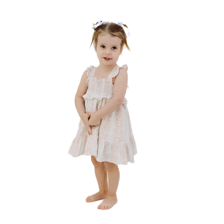 little girl modeling the smocked ruffle criss cross strap dress. 