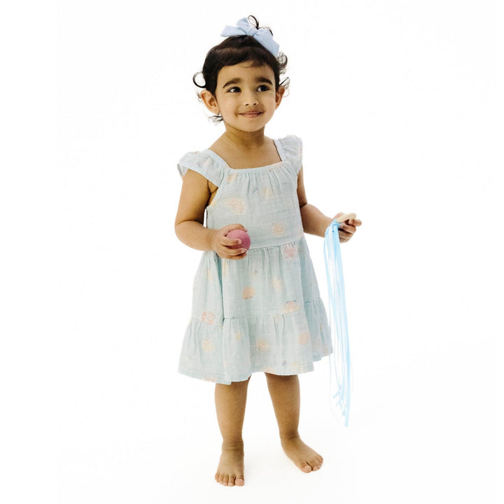 little girl modeling the ice blue seashell dress. hits at the knee and full skirt for movement and twirls 
