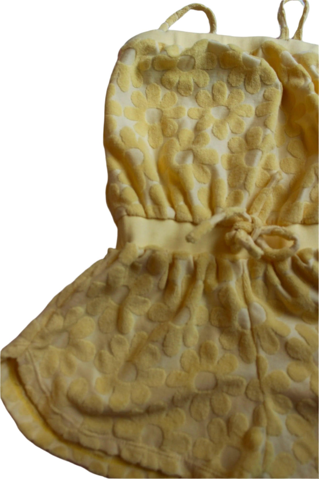 yellow terry romper with daisy printed embellishments all over the romper, spaghetti straps, elastic waist and tie at the waist. 