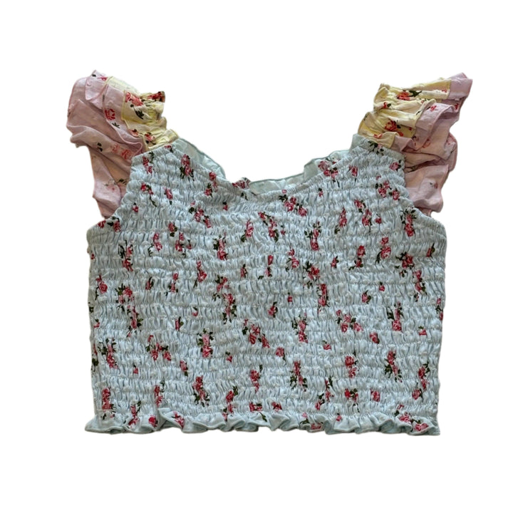 sleeveless smocked top with tiny pink roses all over. blue base of the top and sleeveless ruffles of pink and yellow fabric with the tiny pink roses as well. 