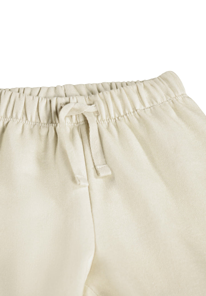 Close-up of a pair of light cream or off-white lounge pants showing the elastic waistband and drawstring.