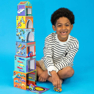 little boy posing next to the tower to show how tall the tower can be stacked when sitting next to it. 