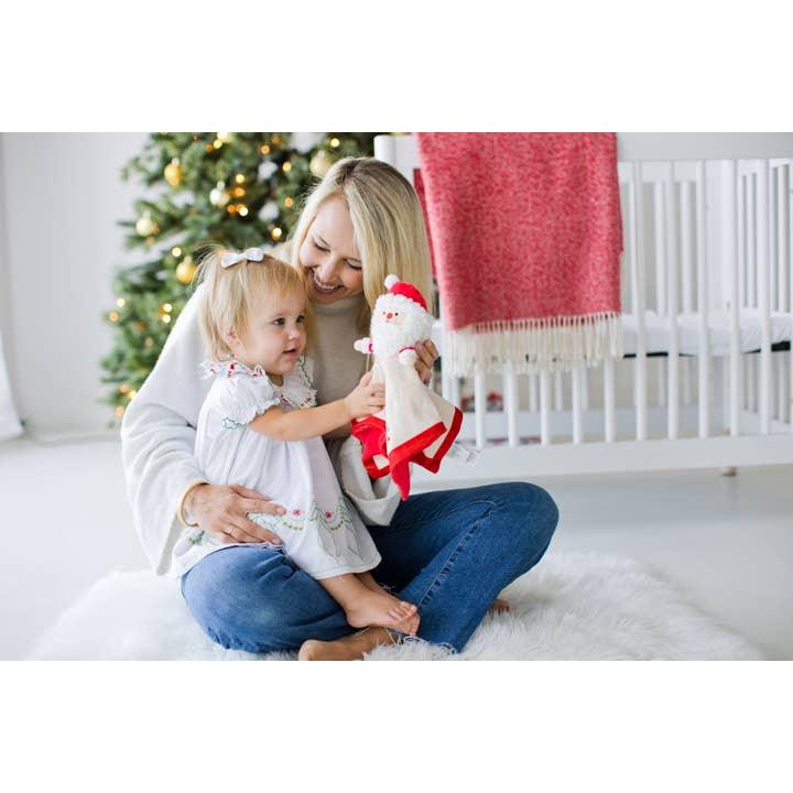 picture of mom holding small baby reaching for the Santa Cuddle toy.