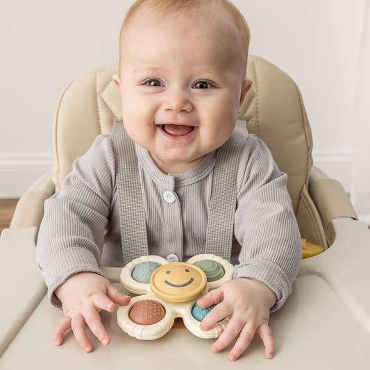 baby playing with suction toy that spins and is attached to the high chair