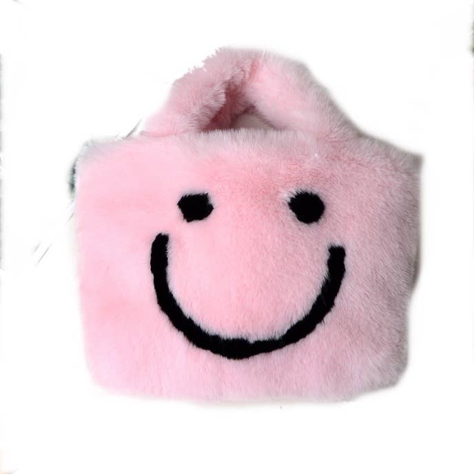 Pink plush handbag with a smiley face design on a white background