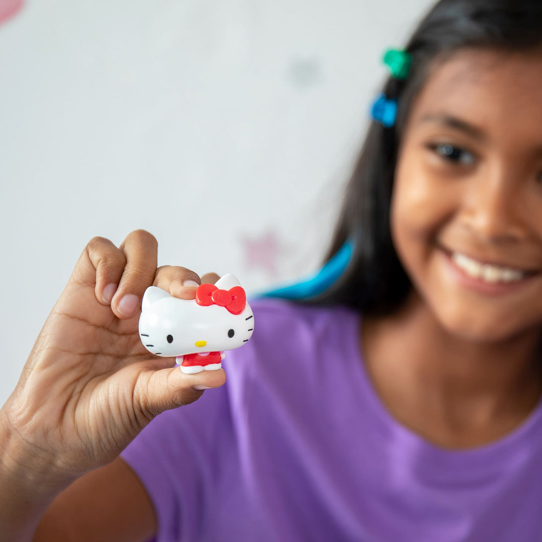 Child holding a small Hello Kitty figurine with a plain background