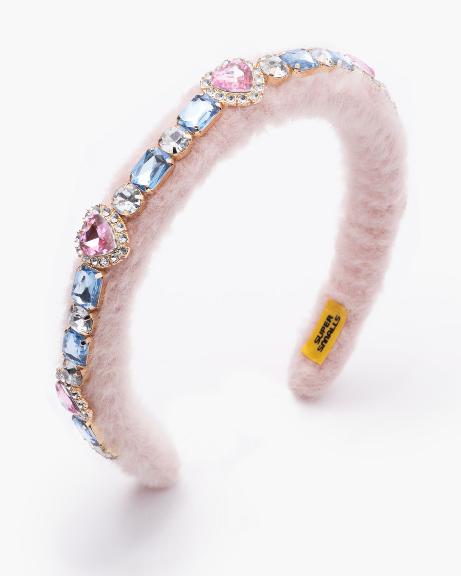 Pink furry headband with colorful gemstones on a white background
