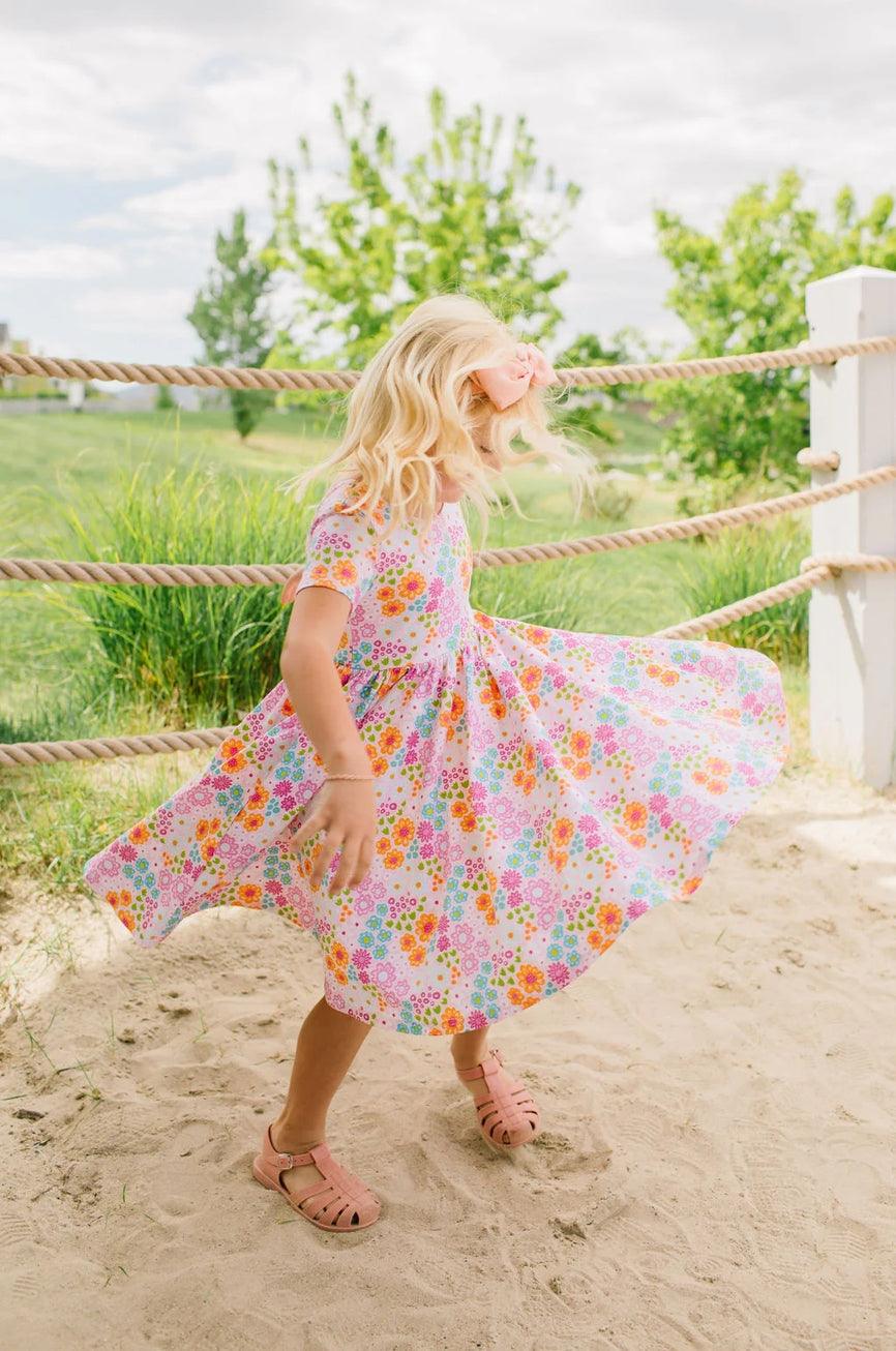 young girl twirling around in the brightly colored floral dress. there is a full skirt for maximum twirl. 