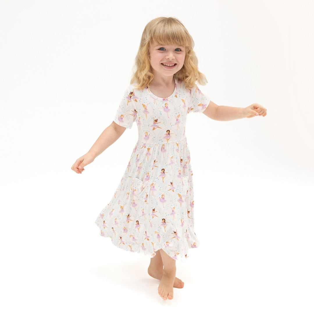 little girl modeling the t-shirt dress with little ballerinas all over it. the dress shows lots of movement and twirl-ability