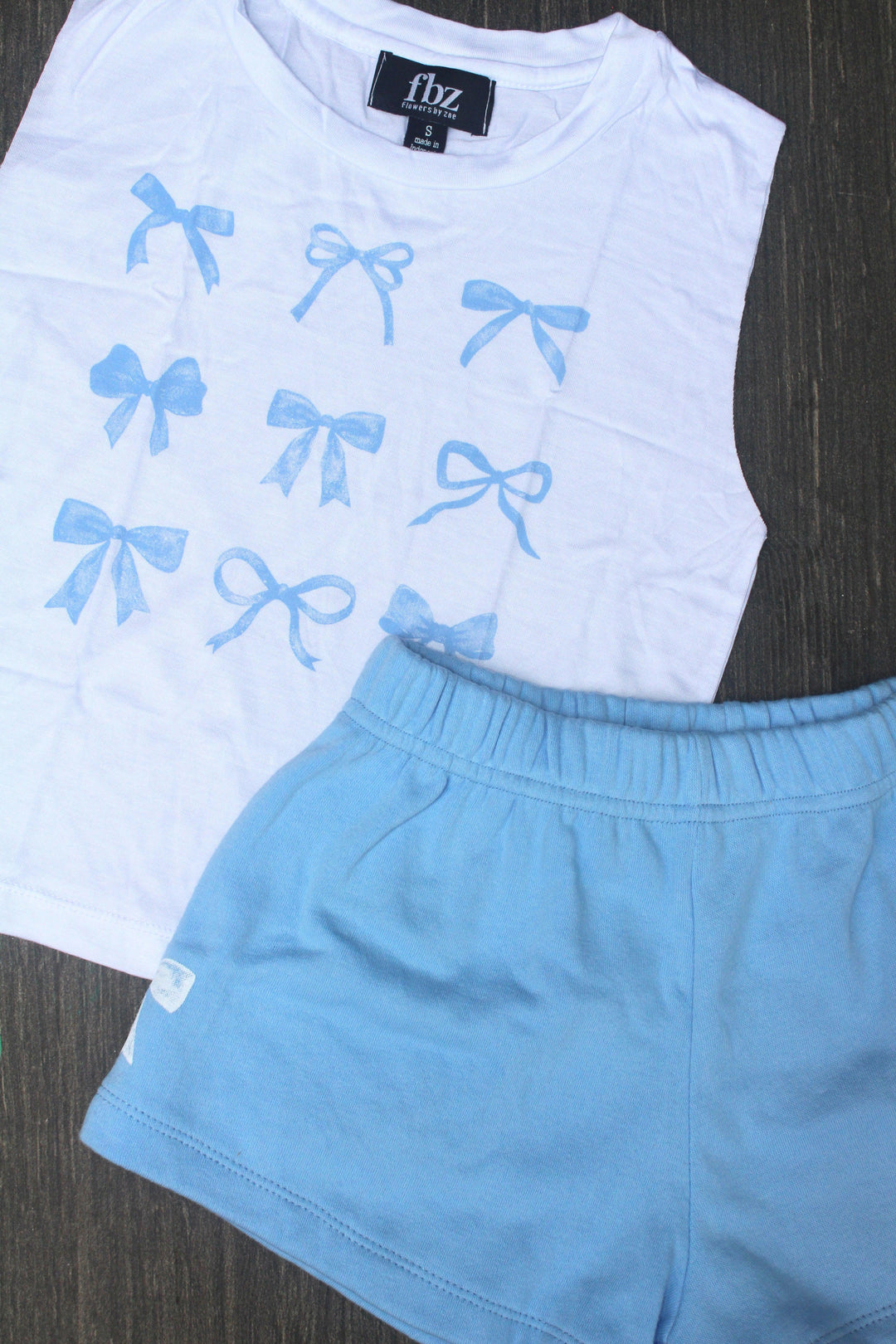 white tank with 9 coquette blue bows and blue shorts with a white bow on the side of the shorts. 