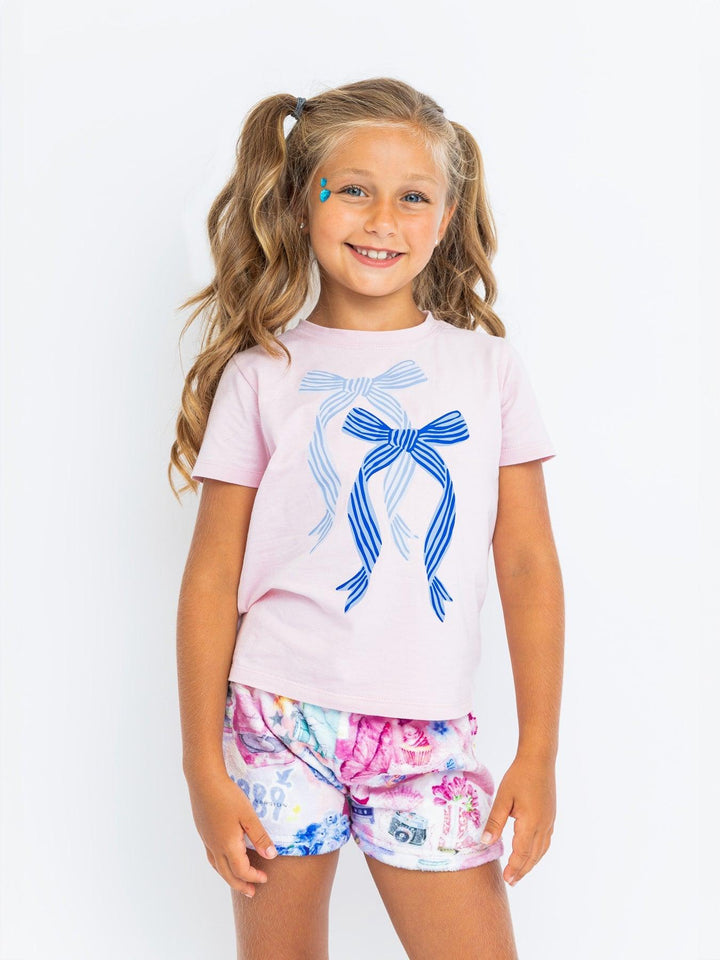 young girl wearing a pink tee and a pair of plush shorts with a music icon print on them. 