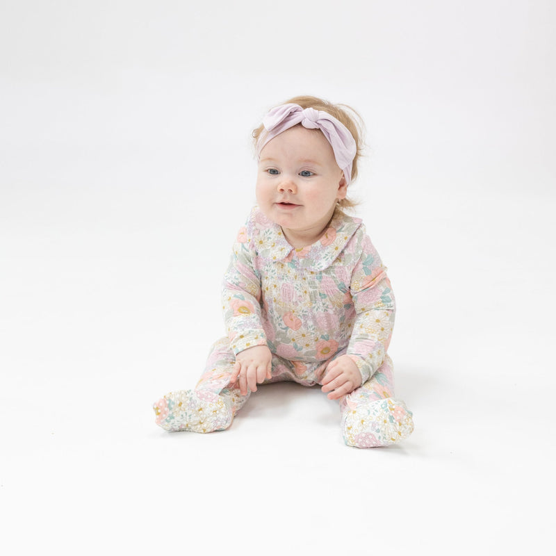 baby girl modeling the footie with pastel flowers and peter pan collar. 