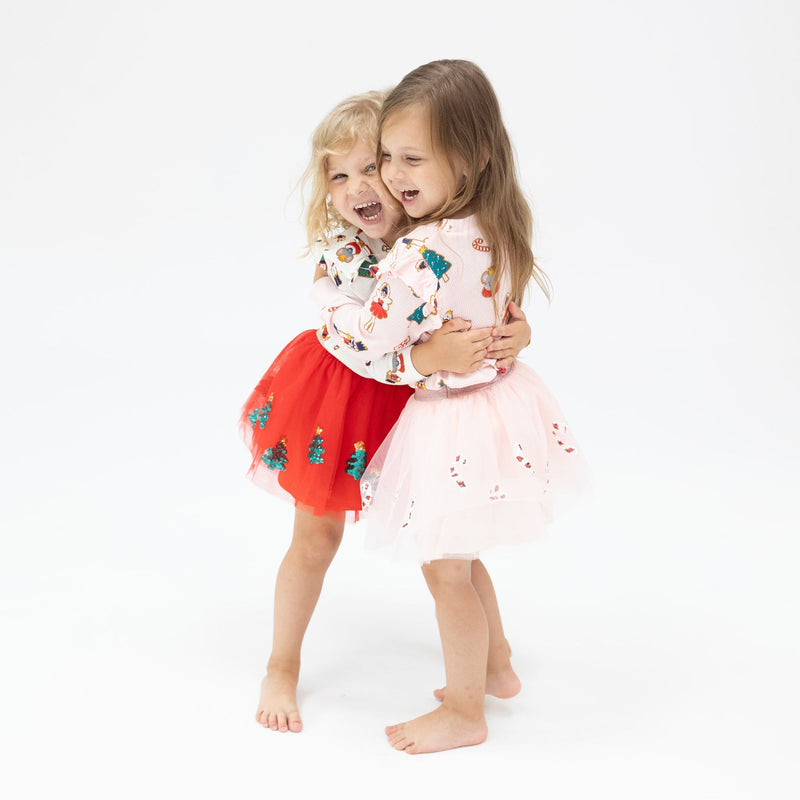 two little girls hugging in their Christmas tutu outfits