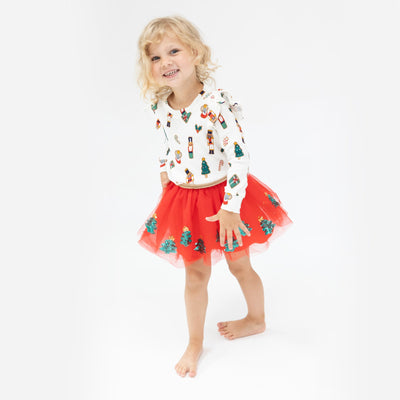 little girl modeling the holiday cookie sweatshirt and red tutu skirt with sequin trees on it. 