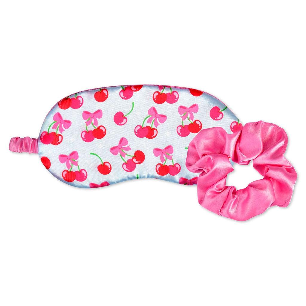 eye mask with light blue background and cherries with a pink bow at the top of the cherries. pink scrunchy comes with the set as well. 