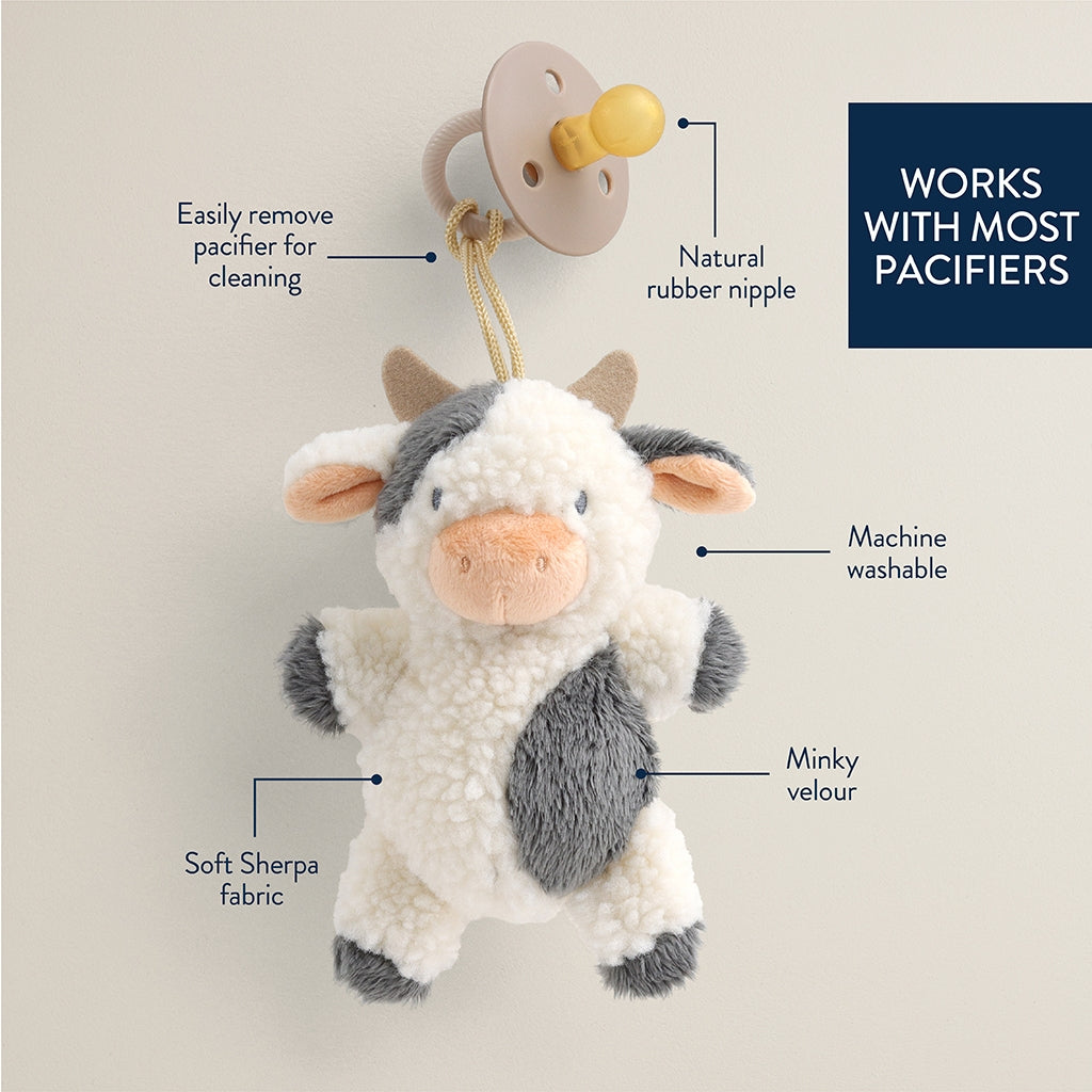 Plush cow pacifier holder with features highlighted on a light gray background