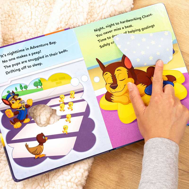 Children's book with a paw print design and a hand interacting with it, on a wooden surface.