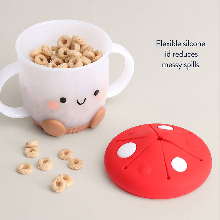 snack cup with open lid with cartoon face filled with cereal, next to a red silicone lid on a light gray background.