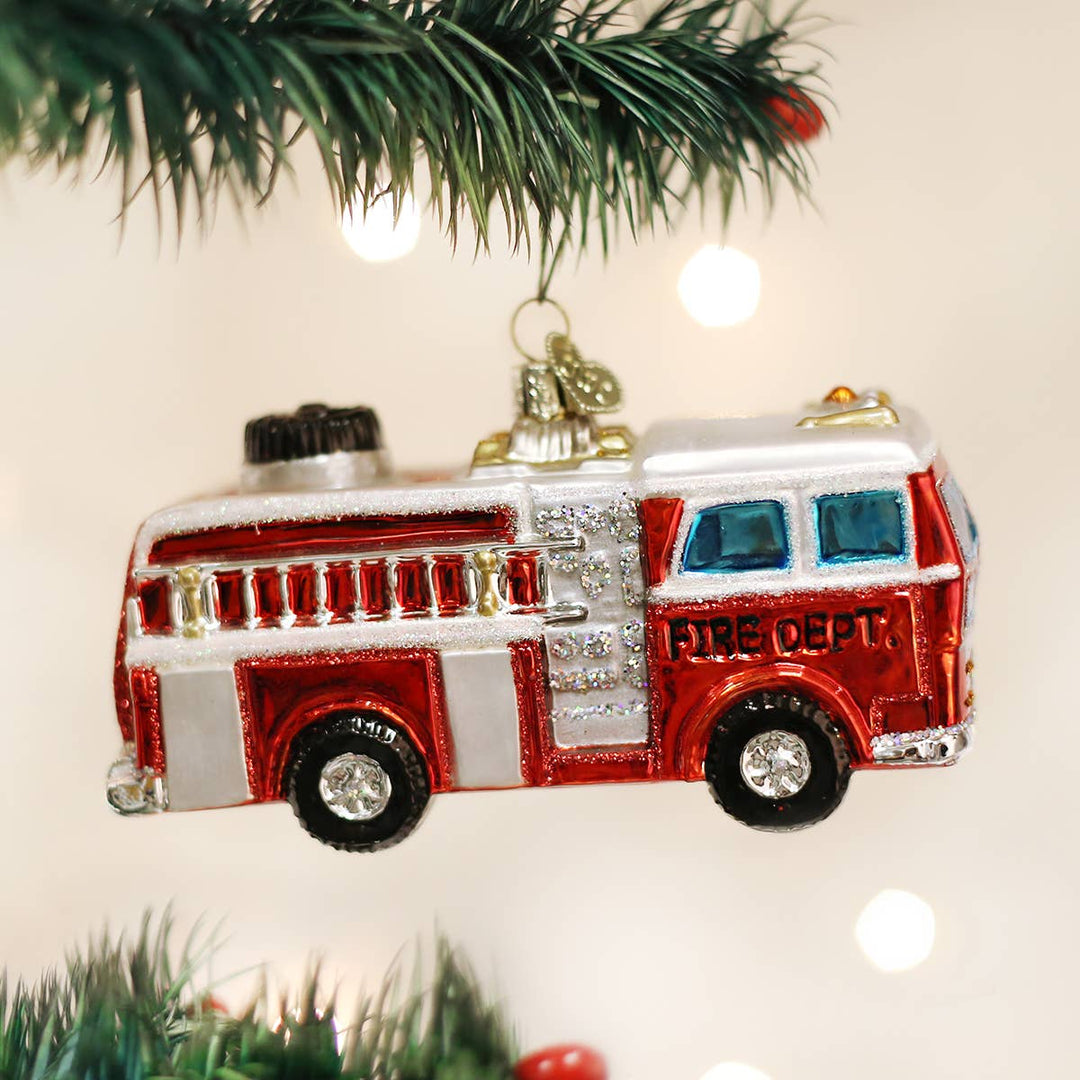 Glass fire truck ornament hanging on a Christmas tree.