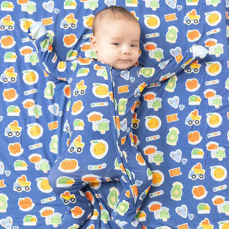 Baby lying on a blue mat with colorful fruit and vehicle patterns