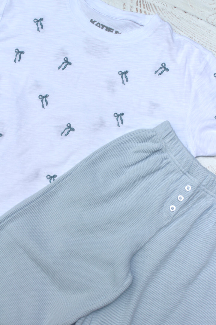 White t-shirt with small black graphics and light gray shorts on a white background