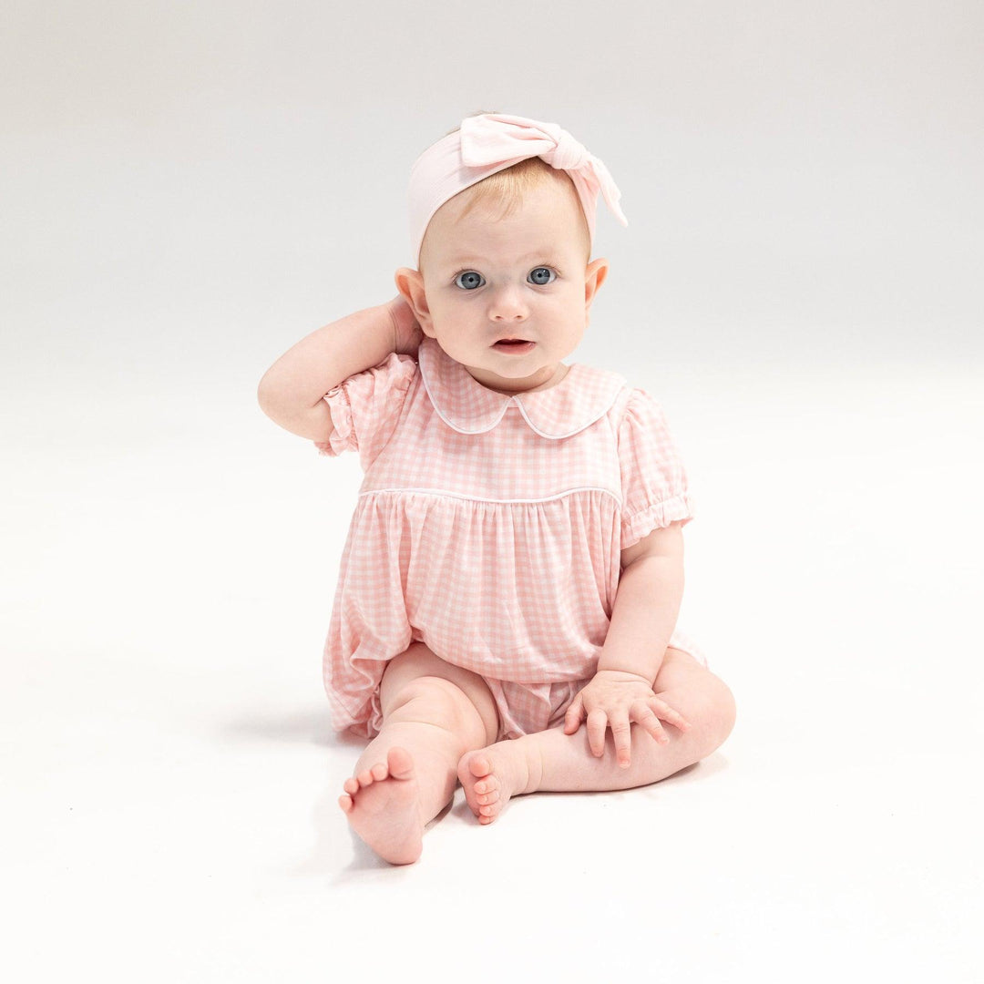 baby modeling the pink and white gingham romper with peter pan collar. 