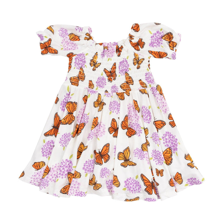 white short sleeve dress with smocking at the top of the dress. purple milkweed flowers and orange butterflies all over the dress. 