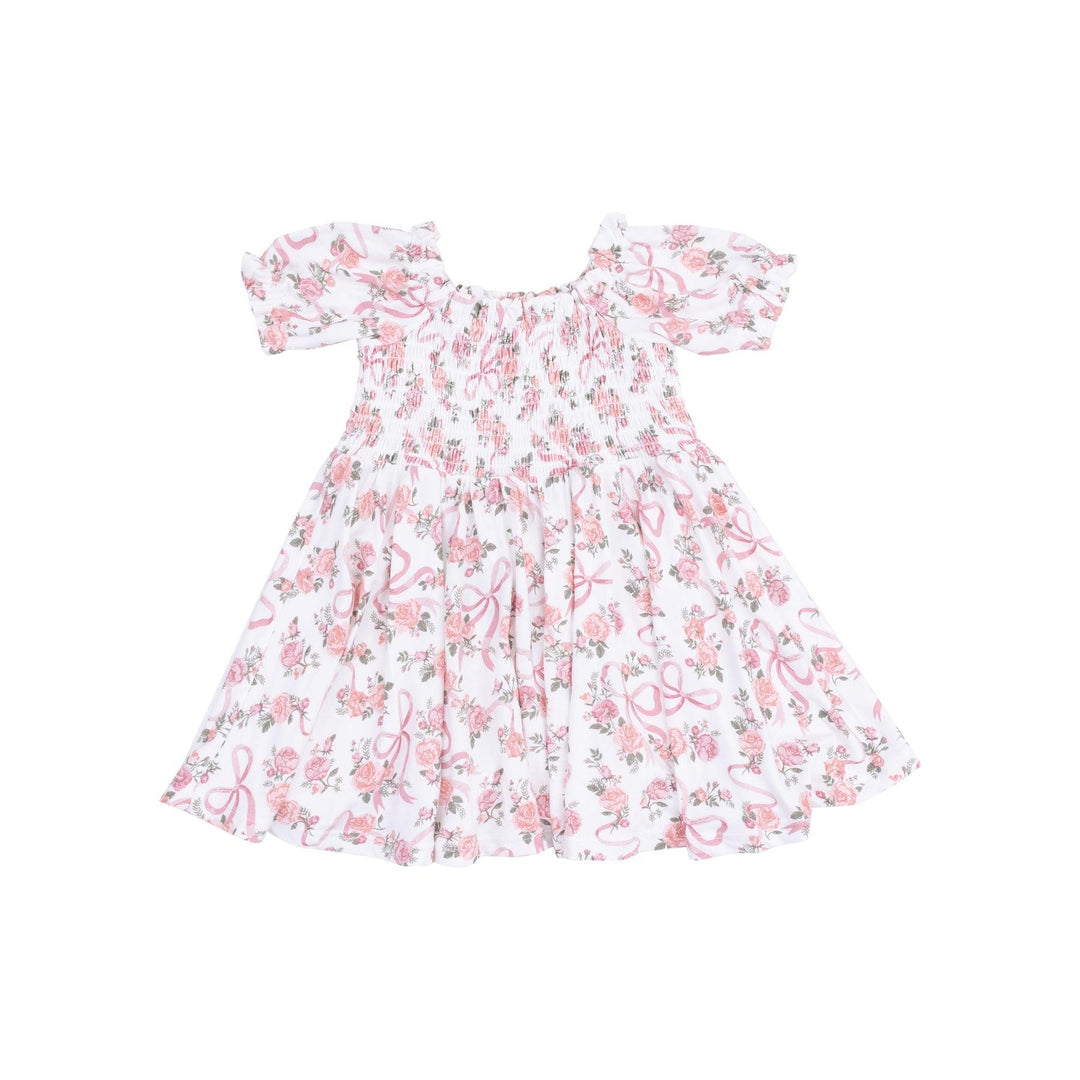 white dress with smocking along the chest and pink ribbons and pink rose bouquets all over the dress. 