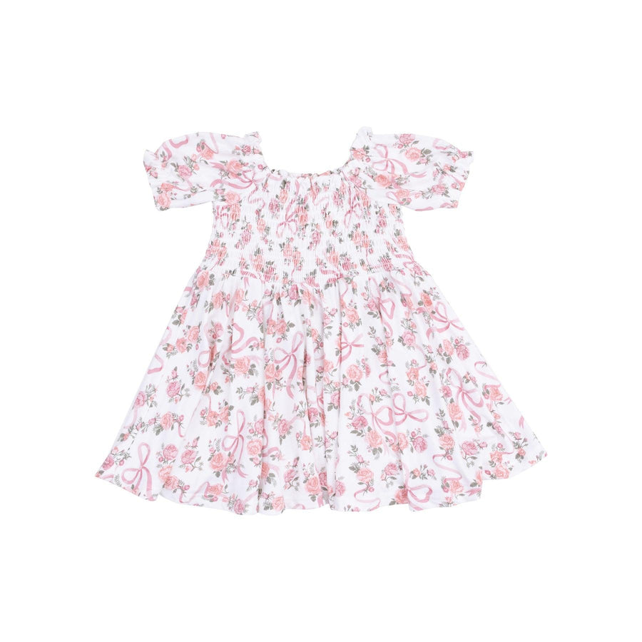 white dress with smocking along the chest and pink ribbons and pink rose bouquets all over the dress. 
