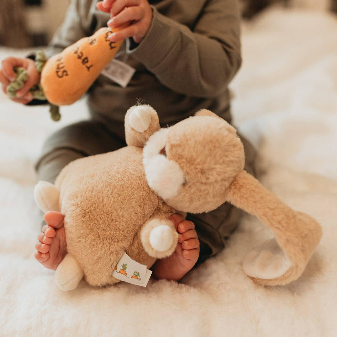 Child holding a plush toy on a soft surface