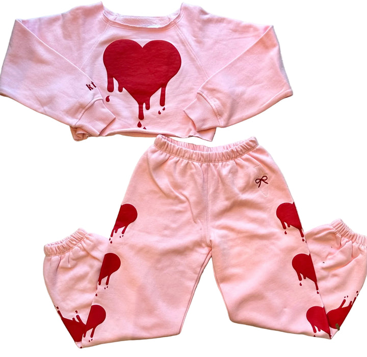 Pink children's outfit with red heart designs on a white background