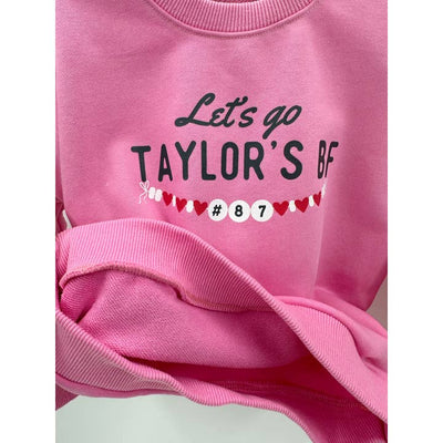 pink sweatshirt that says "lets go Taylor's BF" the inside of the sweatshirt shows the lining of the sweatshirt to be terry and not fleece. 