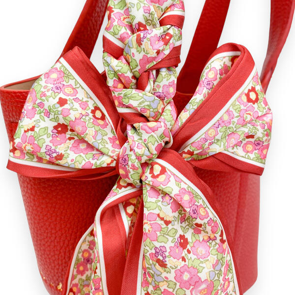 close up view of the red and pink floral scarf tied to the handle. 