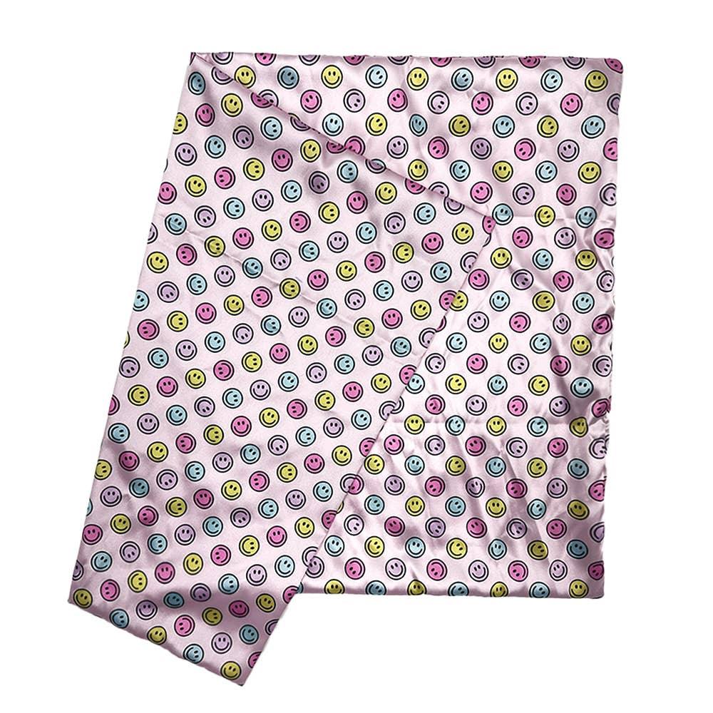 pink satin pillowcase with pink, yellow and blue smiley faces all over it. 