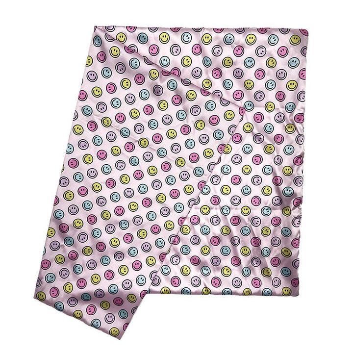 pink satin pillowcase with pink, yellow and blue smiley faces all over it. 
