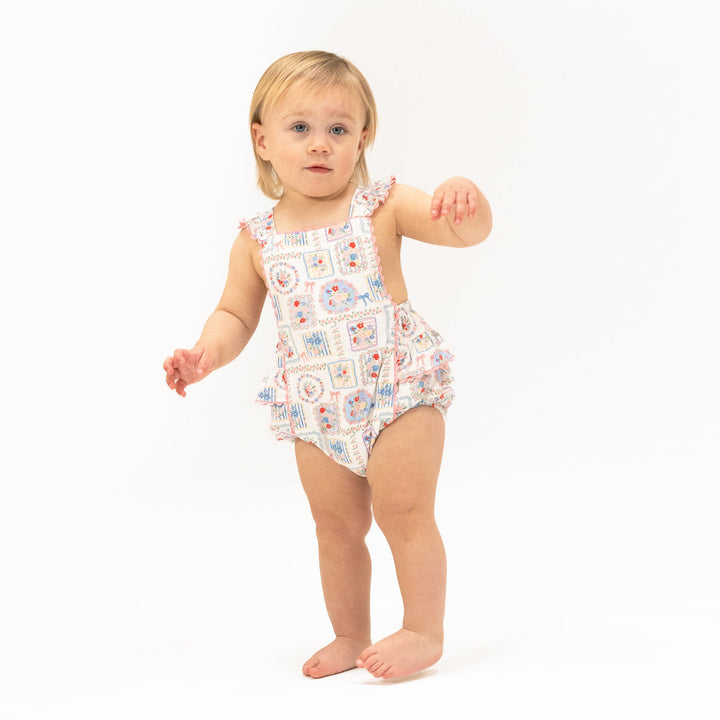 Child wearing a patterned romper on a white background