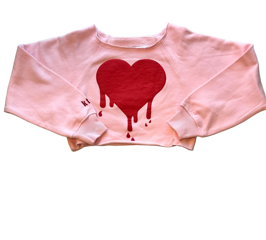 Pink sweatshirt with a red heart design on a white background