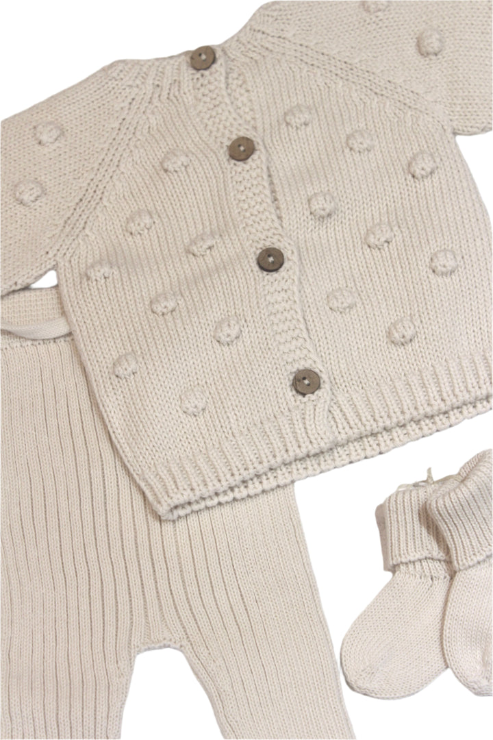 close up of the pom pom sweater cardigan and knit pants. both in coordinating color and fabrics. 