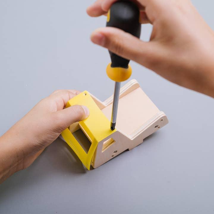 this picture shows someone using a screwdriver to screw in the top of the dumop trck. 