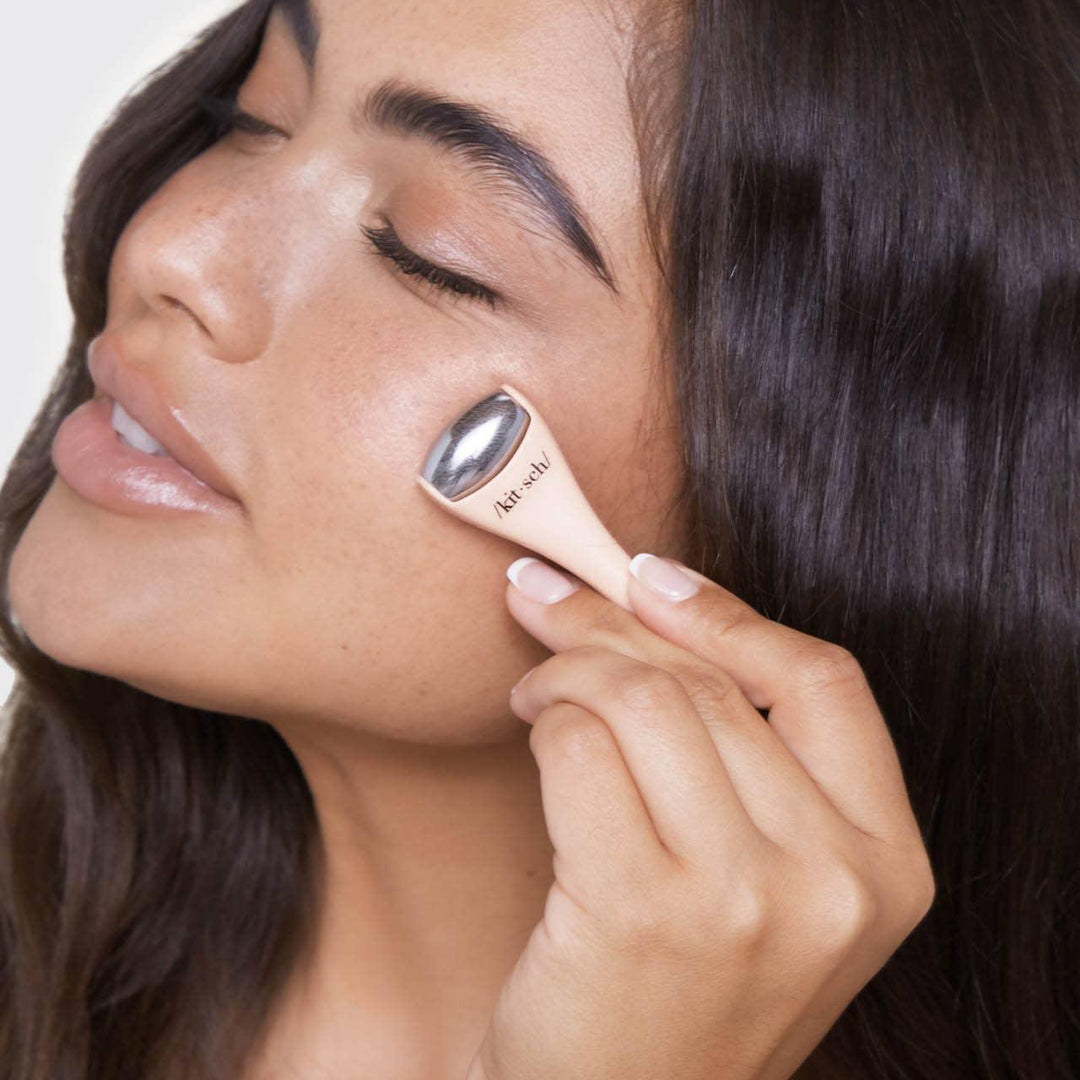 young girl using a small roller on her face. 