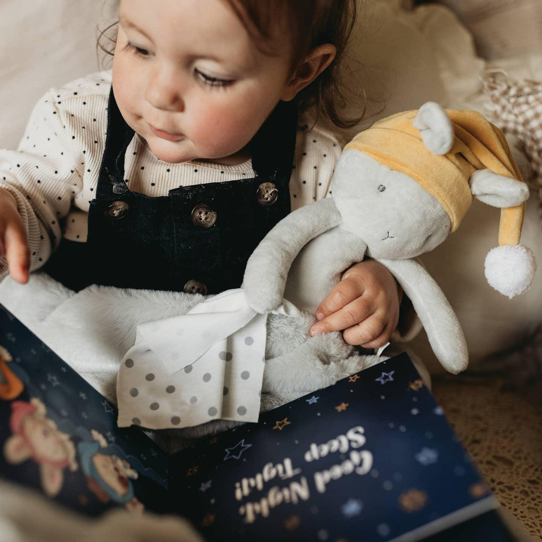 small child cuddling the sleep bloom bunny and a book. 