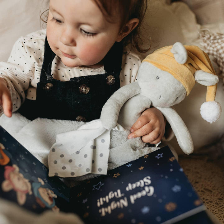 small child cuddling the sleep bloom bunny and a book. 