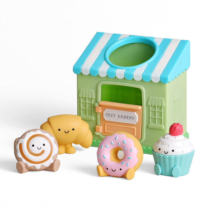Toy bakery set with a green and blue striped roof, featuring a donut, cupcake, and other baked goods on a white background.