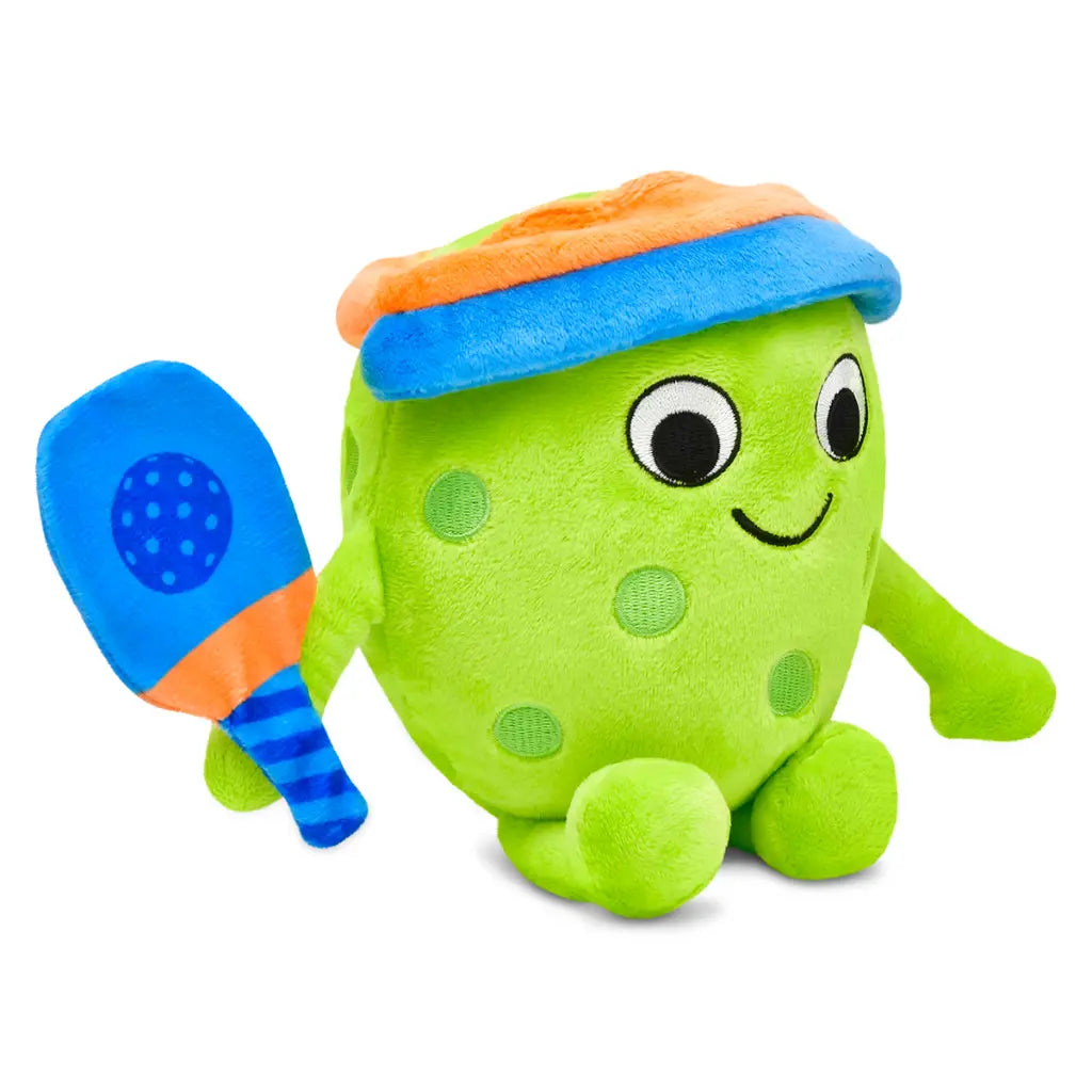 Green plush toy with a blue hat and paddle all in a pickleball theme on a white background